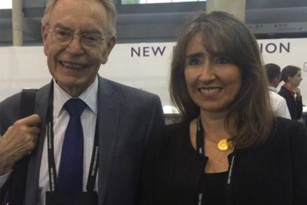 La doctora cardióloga Mónica Acevedo posa para la fotografía en un aeropuerto. A su lado se encuentra el fallecido doctor Ramón Corbalán, cardiólogo UC que la doctora Acevedo destaca como su mentor y quien la motivó a establecer redes de contacto en el extranjero.